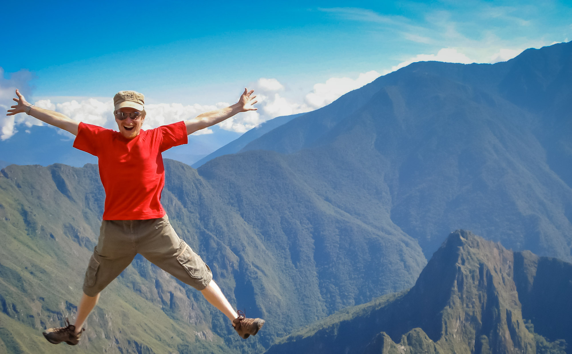 Peru adventure tour guest jumping for joy on Machu Picchu mountain
